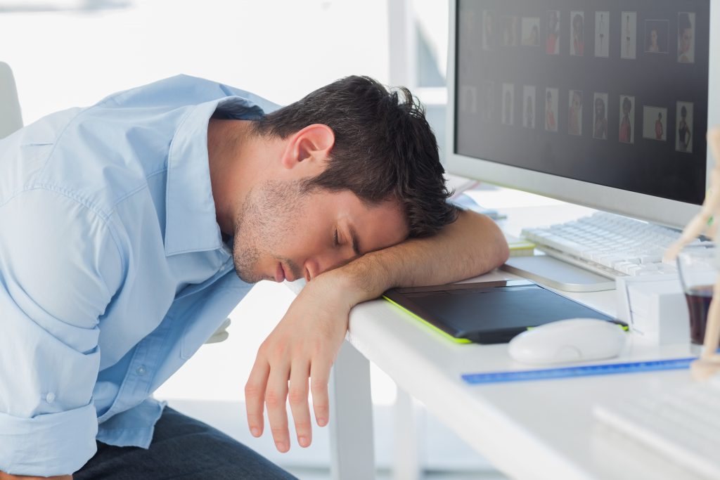 Graphic designer sleeping on the keyboard in his office