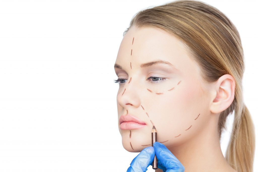 Surgeon drawing dotted lines on pretty patient before surgery