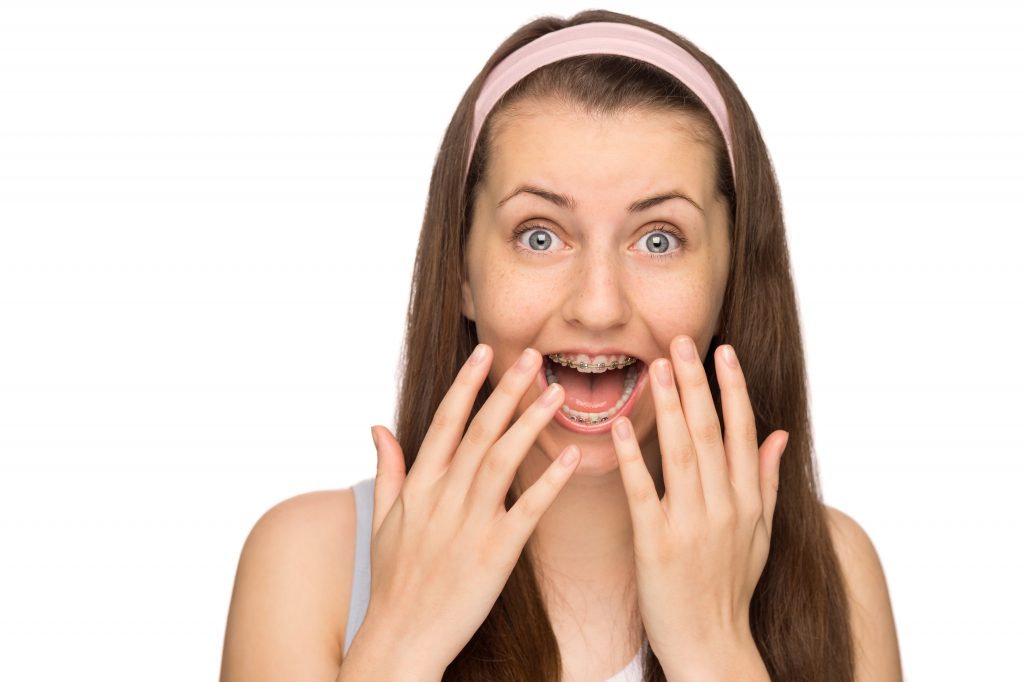 Excited girl with braces shouting teen beauty on white background