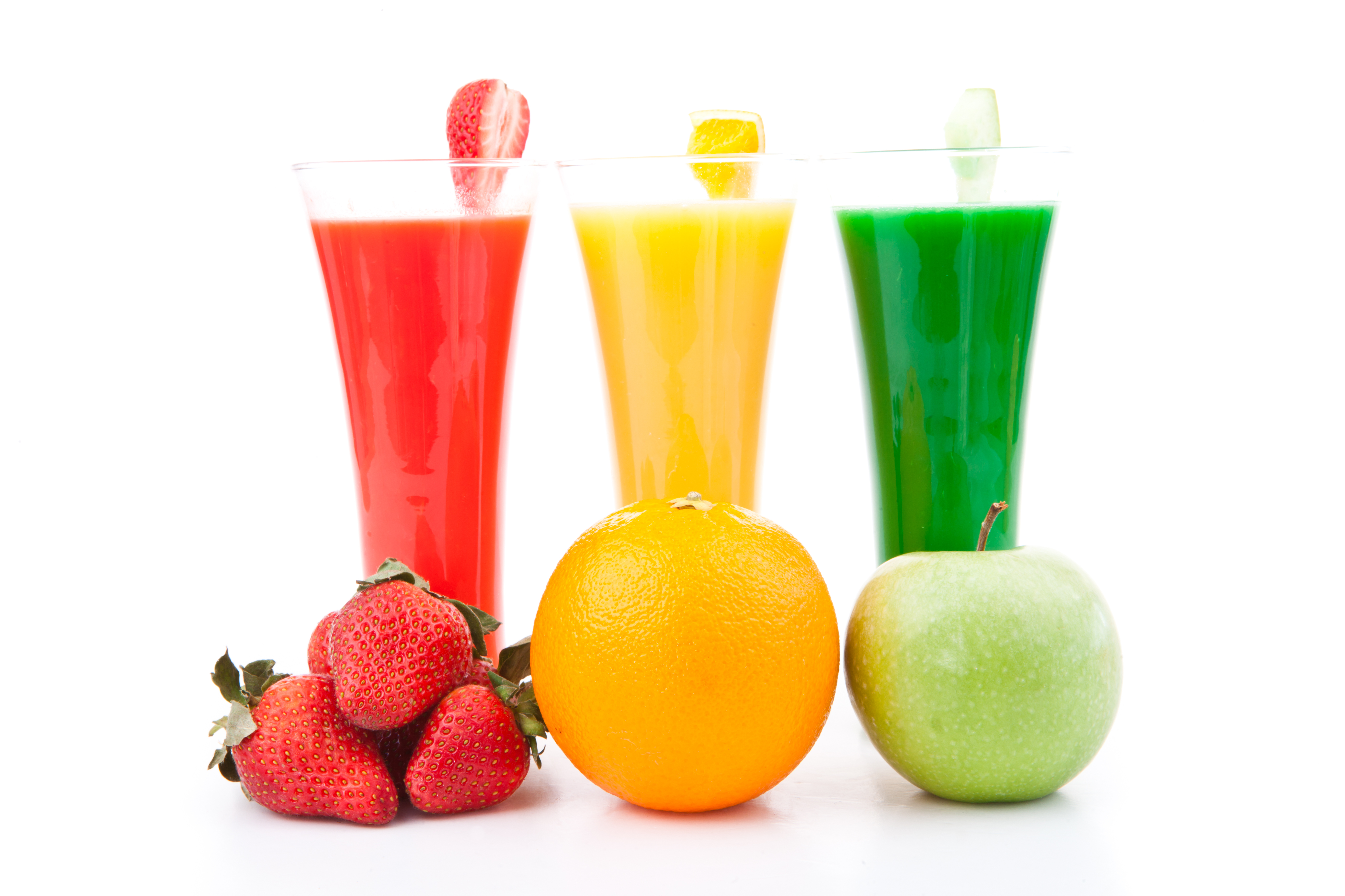fruits placed in front of full glasses against white background