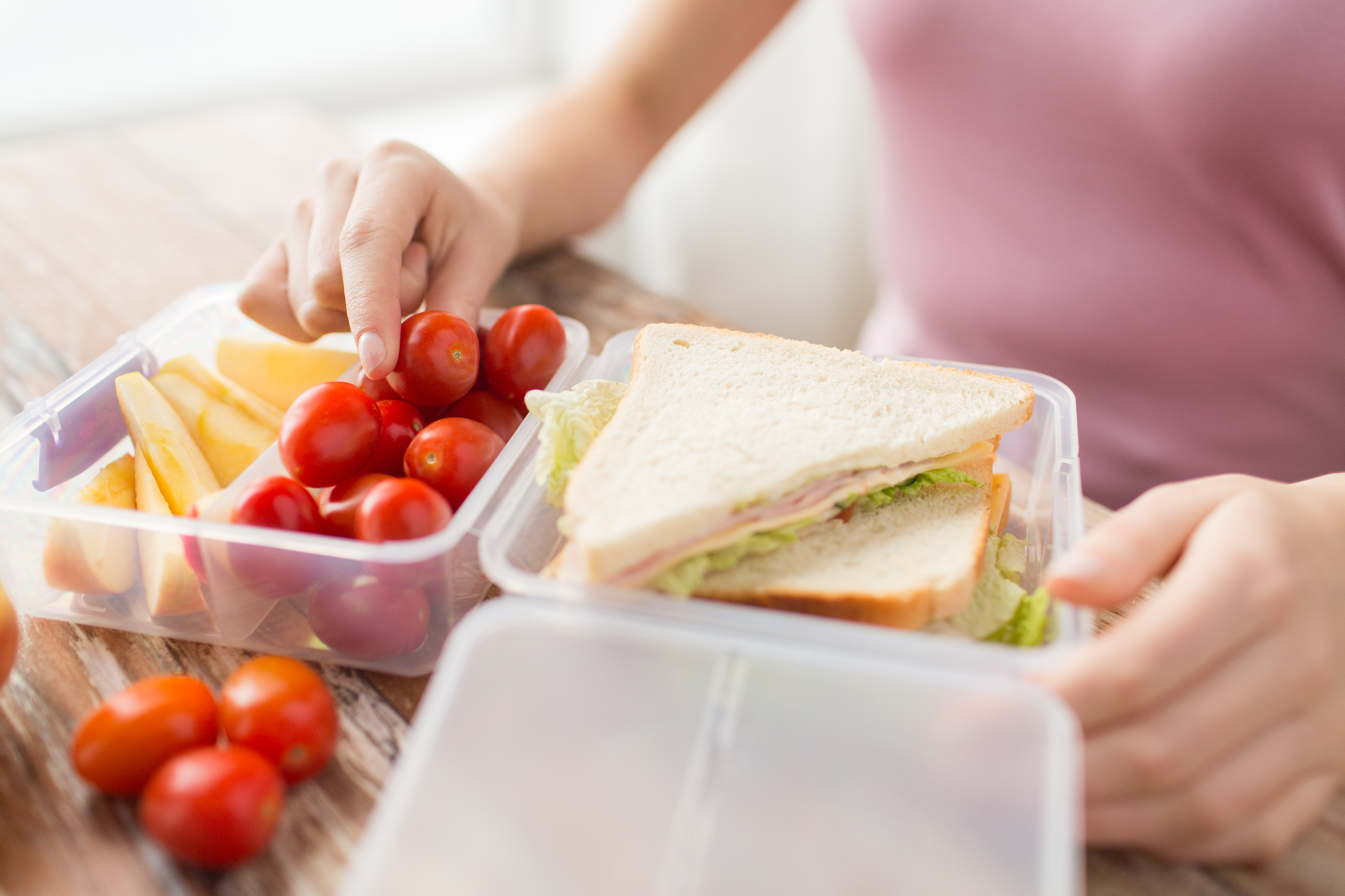 healthy eating, storage, dieting and people concept - close up of woman with food in plastic container at home kitchen