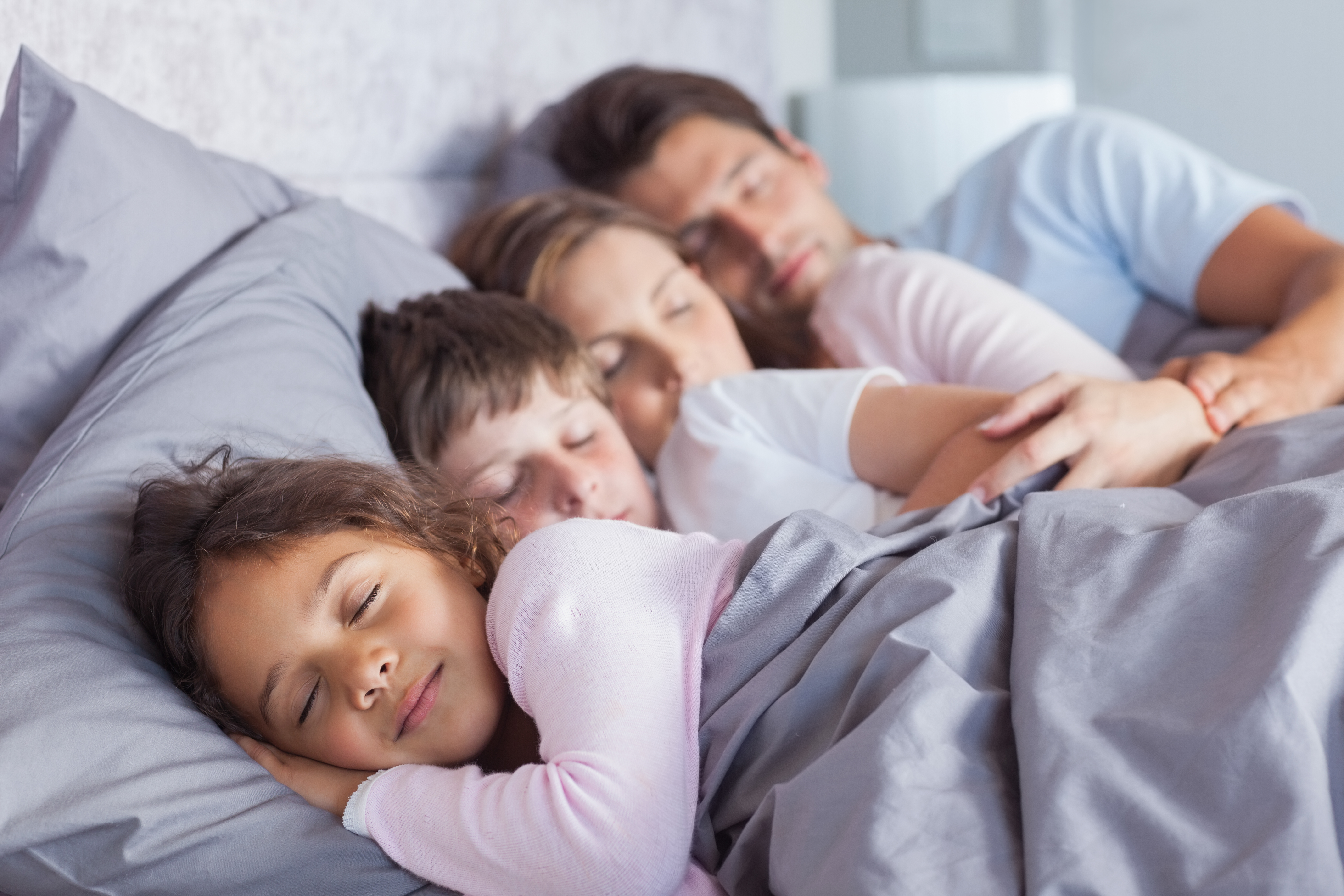Cute family sleeping together in bed